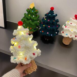 A handmade crochet Christmas tree ornament with textured green yarn, a brown trunk, and small decorative accents.