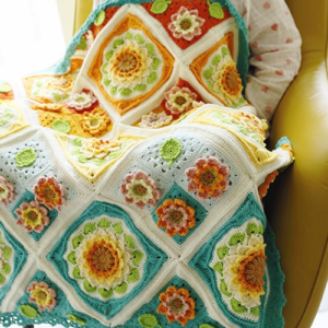 A handmade crochet sunflower blanket with bright yellow petals and a textured brown center