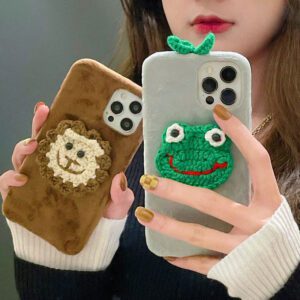 A green knitted frog-themed phone case for iPhone, featuring a cute frog face design with embroidered eyes and a textured finish.