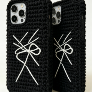Hand-crocheted black cotton phone case with a sleek, textured stitch pattern, featuring a minimalist design and a snug fit around a smartphone, displayed on a clean white surface with soft natural lighting.