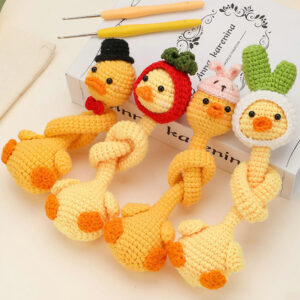 Long neck duck crochet kit for beginners, featuring soft yellow and orange yarns, a crochet hook, stuffing, safety eyes, and a finished plush duck with an extra-long neck and tiny wings, displayed on a light wooden background.
