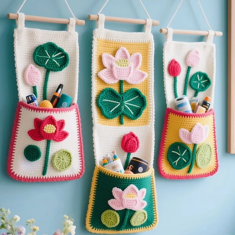 Crochet lotus flower wall organizer with pink and white petals and storage pockets hanging on a wall.