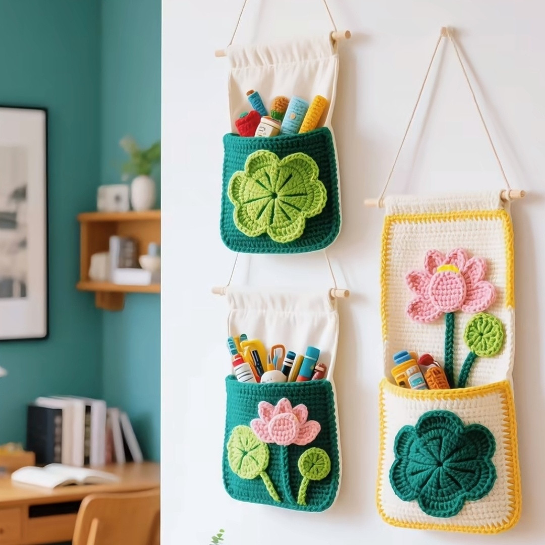 Crochet lotus wall pocket with pink and white petals and a front storage pocket hanging on a white wall.